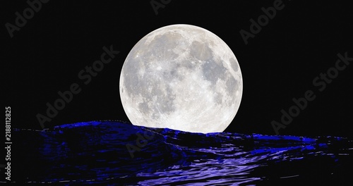 full moon in the night over ocean surface with reflection on it during stormy waves