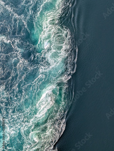 Картината върху платно Boundary between churning turquoise foam and smooth dark water in a strong tidal