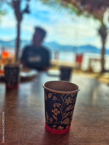фотографія Disposable Paper Coffee Cup with Floral Pattern at Beachside Cafe