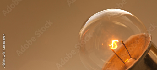 Glass bulb close-up with burning element inside, glowing light. Idea concept, energy poster, bright innovation banner
