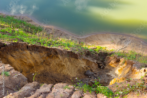Canvastavla Severe soil erosion of a sandy hillside bordering a tranquil pond, showing deep