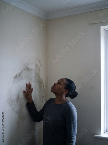 Tenant examining a damp patch on her bedroom wall