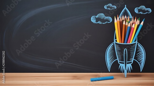 Creative rocket drawn with chalk on a blackboard filled with assorted colored pencils for back to school and education concepts