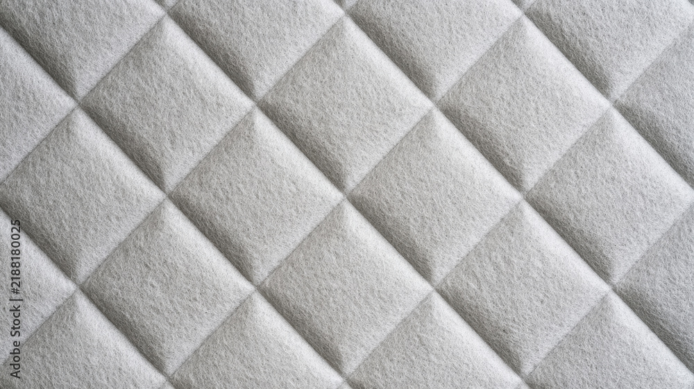 Fototapeta premium Quilted light gray textured fabric presenting a repeating diamond pattern, forming an elegant background for textile design, interior decor, and soft furnishing concepts