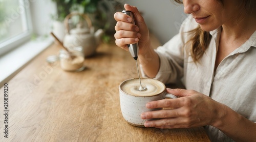 Morning ritual captured as hands delicately froth velvety milk into a warm ceramic mug of rich artisan coffee upon a rustic wooden kitchen counter