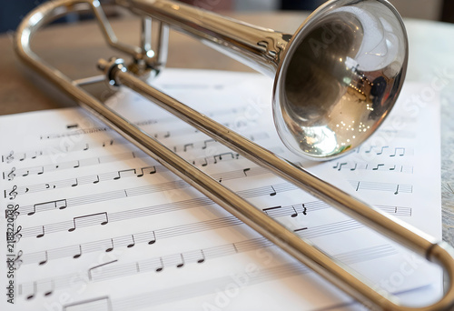 Music education and performance, silver trombone resting on sheet music for classical orchestra practice, creative arts and hobby inspiration in studio