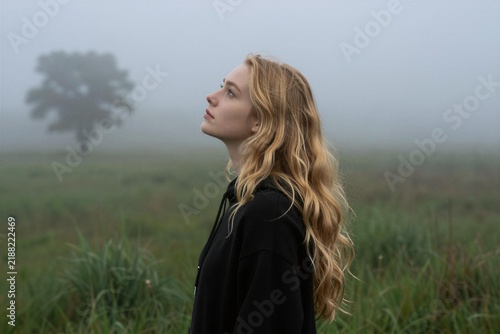 Lonely Blonde Woman in Misty Field Looking Up