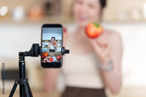 Asian woman recording healthy food vlog video with smartphone in kitchen