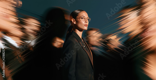 Confident Business Leader With Glasses Standing Out Amid Abstract Crowd Motion