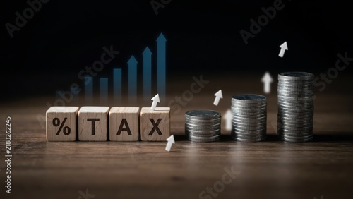 Wooden blocks with tax percentage symbol and stacks of coins with rising arrows representing increasing financial burden and economic tax growth