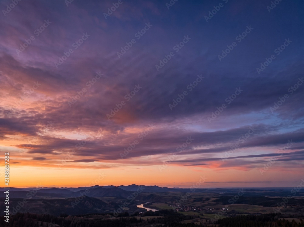 Fototapeta premium Panoramic Sunset over Mountain Valley and Winding River Under Dramatic Purple Sky
