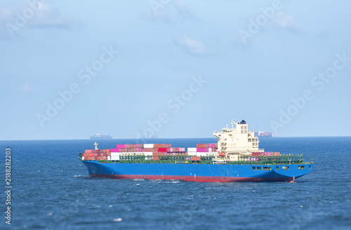 Canvas Print Large container vessel underway near the Chinese coastline in bright sunshine, with cargo containers stacked across the deck