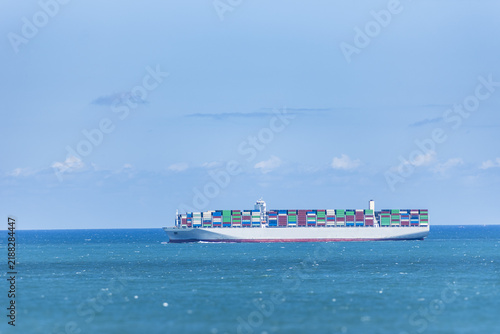 Foto Fully loaded container ship sailing along the Chinese coast on a sunny day, carrying stacked containers and illustrating international maritime transportation and global trade