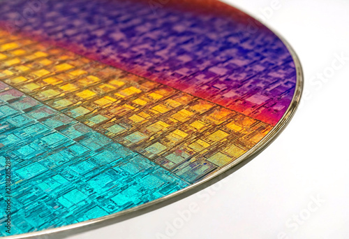 Closeup view of a colorful semiconductor wafer with intricate microchip patterns and vibrant rainbowlike surface reflections