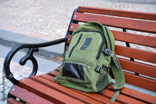 Unattended backpack left on a public bench in a pedestrian area, illustrating a forgotten personal belonging and public safety concern.