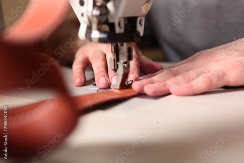 Картината върху платно Close-up hands guide red leather under industrial needle