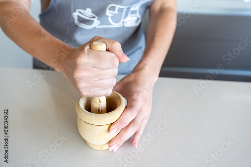 Принти на полотні Woman hands crushing ingredients in a wooden mortar with a pestle on a kitchen c