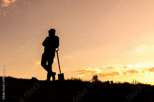 Bild auf Leinwand Waiting and Thinking, Silhouette with Shovel and Hat