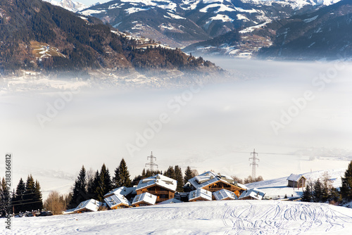 Bild auf Leinwand Snowy Zell am See Kaprun valley lies beneath forested Austrian Alps, partly hidden by dense winter fog