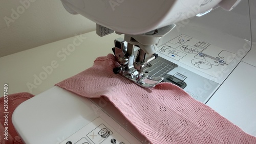 Fotografie Close-up view of a sewing machine presser foot stitching fabric during the sewing process