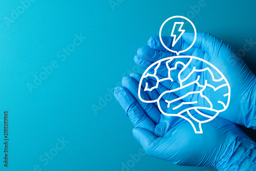 Doctor hands in blue medical gloves holding a digital brain graphic with a lightning bolt on a blue background. Concept of neurology, mental health, epilepsy, stroke, and psychiatry.