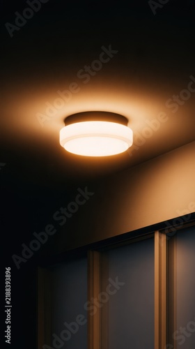 A modern ceiling light casts a warm glow in a dimly lit room with stylish cabinetry