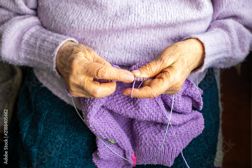 Canvastavla Elderly woman knitting a purple sweater by hand, cozy hobby and tradition at hom