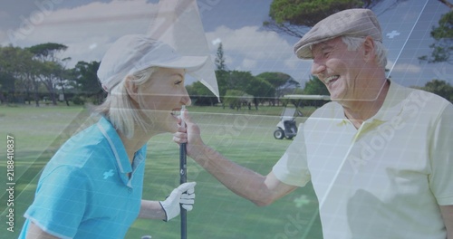 Fotografie Smiling mature woman and senior man handling flagstick on golf green, wearing po