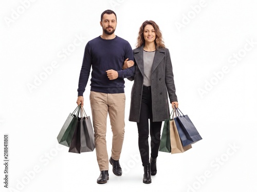 Young adult couple walking together linking arms while carrying various colorful shopping bags.