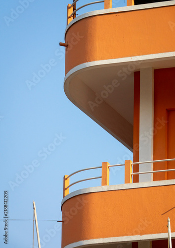 Curved balconies of an orange modernist building rise against a clear blue sky, Luanda Province, Luanda, Angola