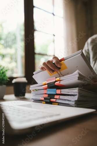 Obraz na plátně A close-up shot of an Asian woman handling a large volume of documents and files, dealing with organization, management, deadlines, workload, bureaucracy, and business responsibilities