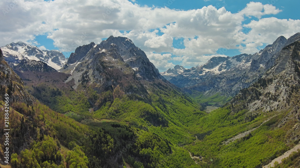 Fototapeta premium Rocky snow mountains and green valley aerial