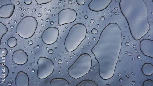 Bild auf Leinwand Water droplets on smooth gray surface forming abstract pattern, highlighting purity, freshness, surface tension and clean minimal background for hygiene, technology or design concepts