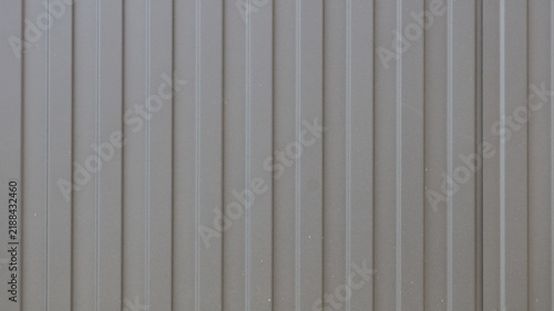 Surface made of brown profiled metal sheeting; uniform texture of corrugated wall paneling with vertical ribs. Used for cladding facades, fences, and rapidly assembled structures