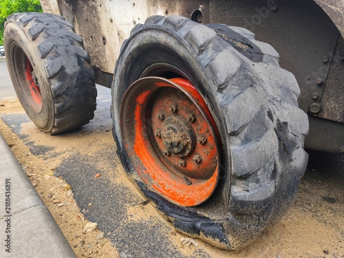 Bild auf Leinwand Pair of rugged skid steer loader tires with orange rims and deep tread showing w
