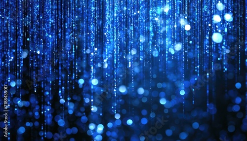 Abstract blue bokeh particles descend like shimmering, illuminated rain in darkness