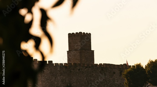 Ancient stone castle tower behind defensive walls at sunset Architecture