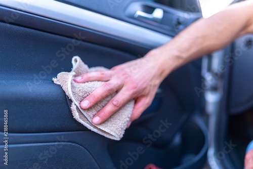 Man wiping inner side door panel of car with cloth