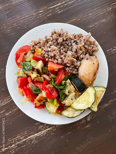 Top view of plate with balanced meal of buckwheat, chicken, fresh vegetable salad and baked zucchini, healthy eating and nutrition