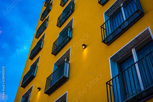 Vibrant yellow building facade with blue sky and balconies