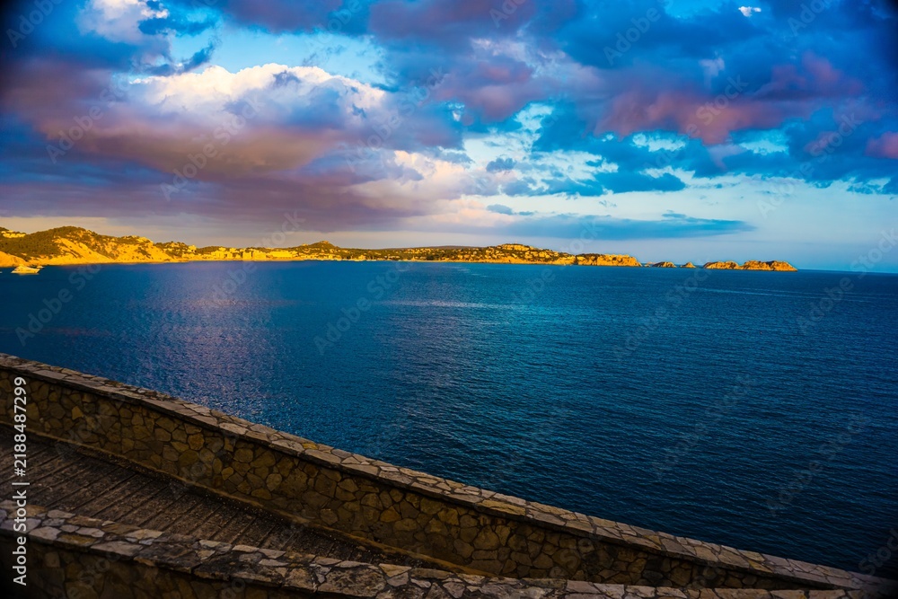 Fototapeta premium Dramatic sunset over a coastal landscape with blue ocean