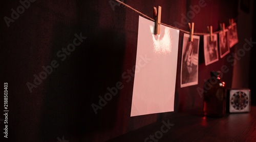 Принти на полотні Blank photograph hanging to dry on line in red lit darkroom