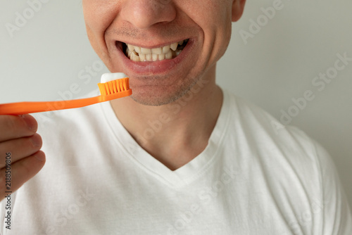 Foto Young man brushing his teeth with a toothbrush at home, daily oral hygiene and dental care routine