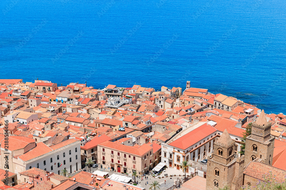 Fototapeta premium A picturesque coastal town with historic architecture and orange tiled roofs overlooks the deep blue Mediterranean Sea from above