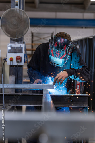 Fotografie Arc welding a steel frame with sparks in a workshop