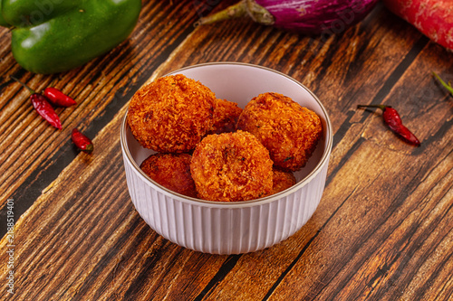 Quadro su tela Crispy golden fried croquettes in white ceramic bowl on rustic wooden table with