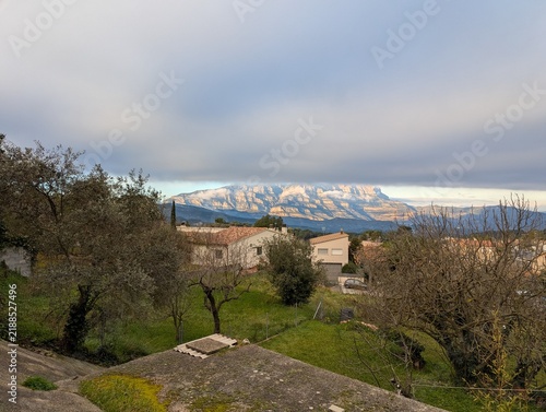 Snow capped mountain range overlooking a rural village landscape at sunset
