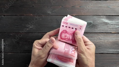 A close-up, enlarged top-down view of a stack of 100 yuan banknotes being deftly counted by hand.
