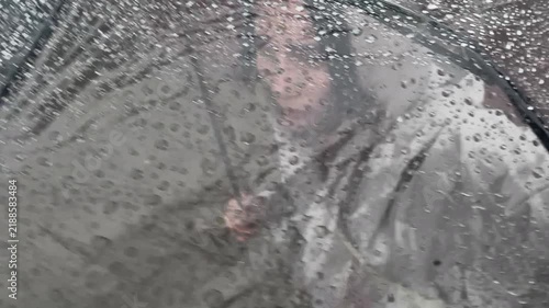 Top profile view of a woman walking outdoors under a transparent umbrella during a rainy autumn day