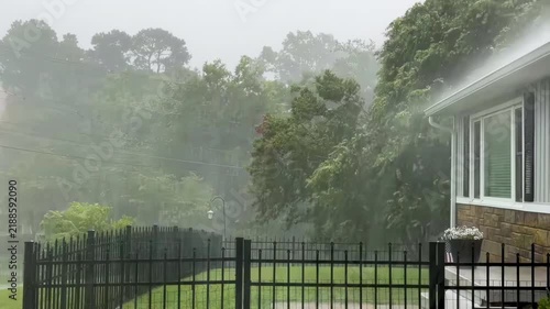 A thunderstorm with heavy rain pouring down violently on a home.

